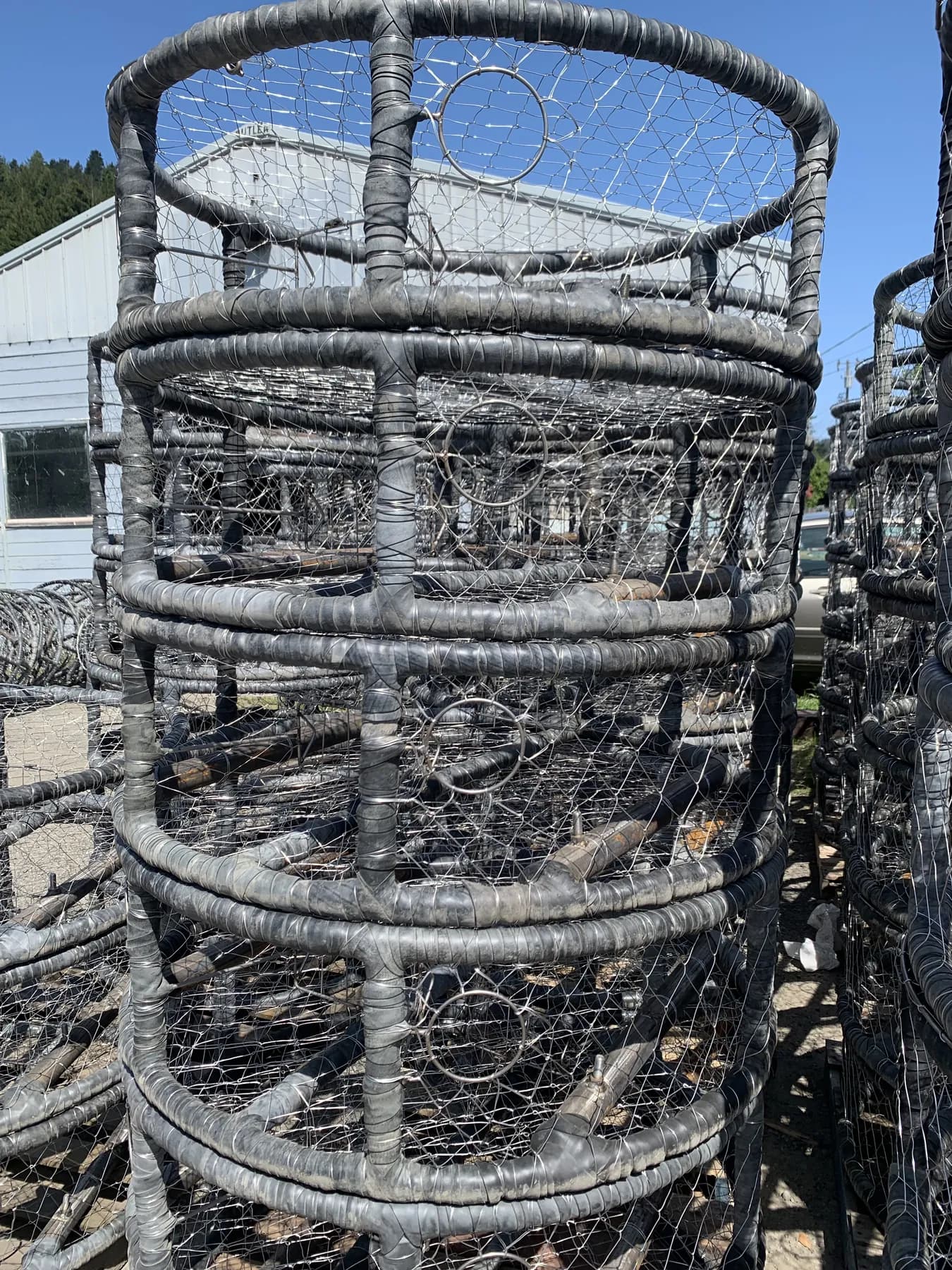 Stack of finished CCP crab pots in the sun, rubber-wrapped frames and knitted stainless wire